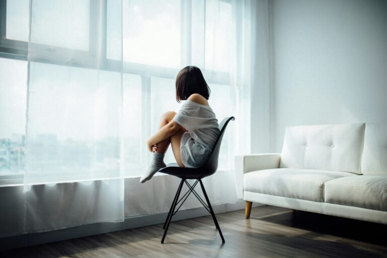Mujer sentada junto a una ventana en una habitación iluminada